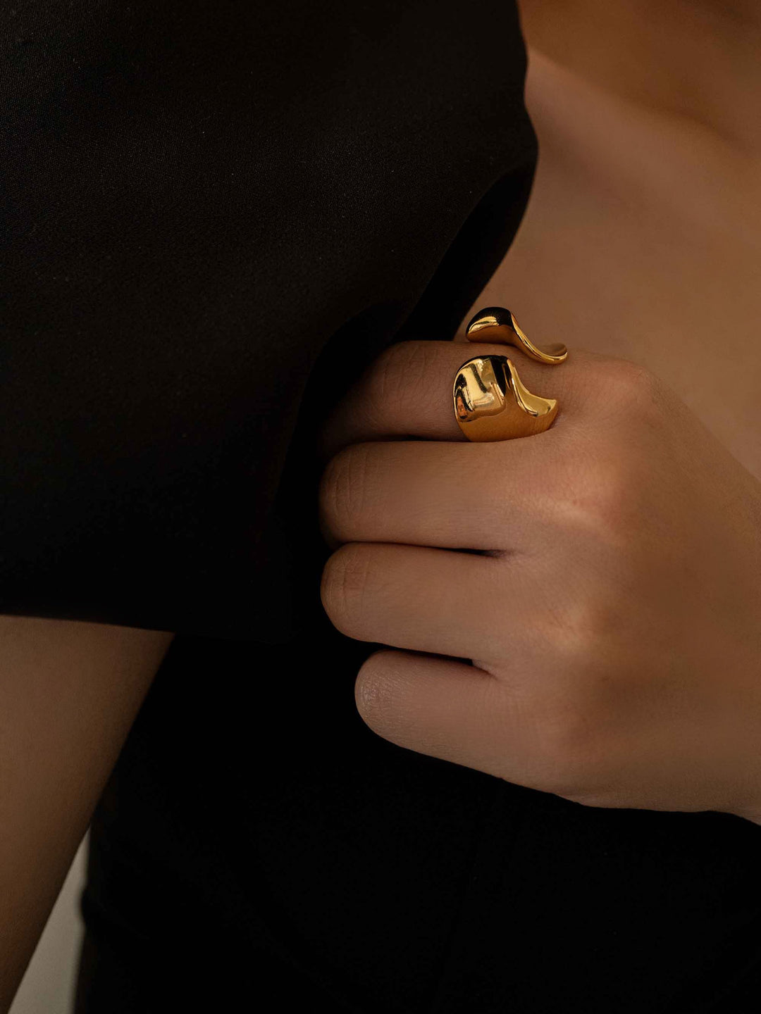 a hand wear A gold ring in the shape of a sea wave