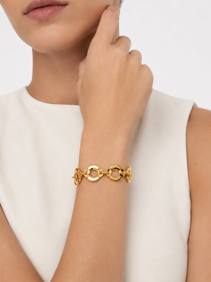 Gold-plated sculptural link bracelet worn with white outfit