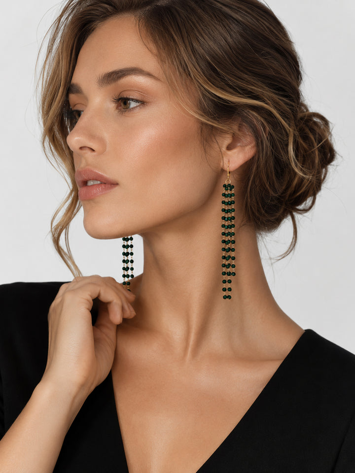 Long green stone drop earrings worn with black dress