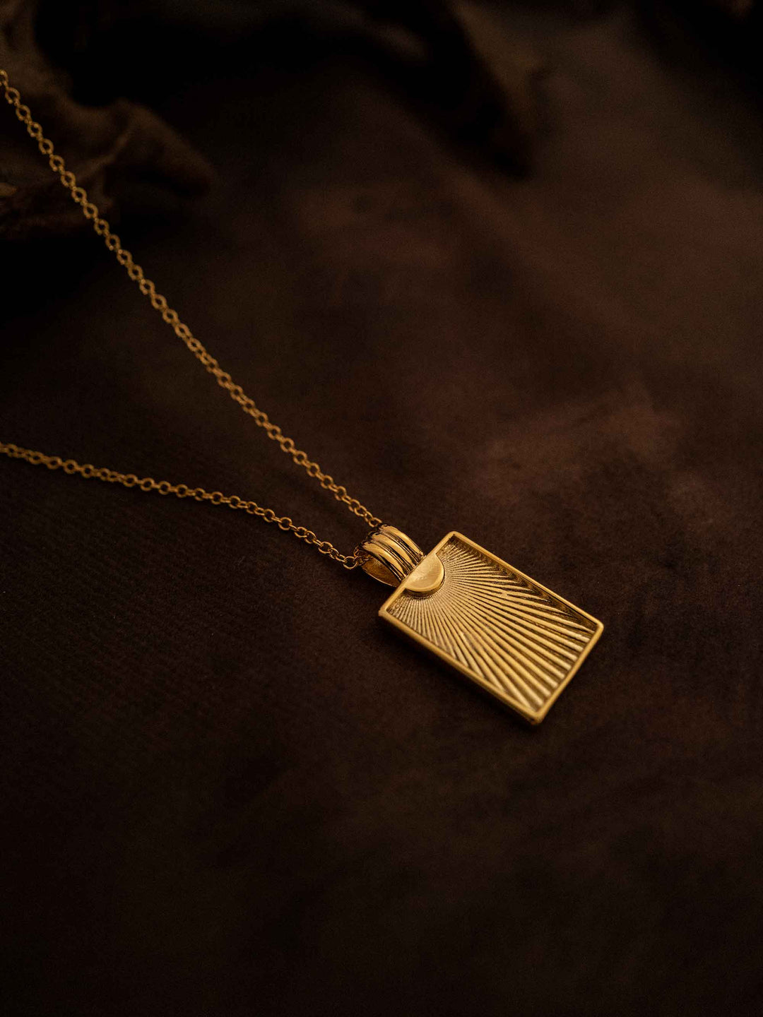 A gold necklace with a rectangular pendant