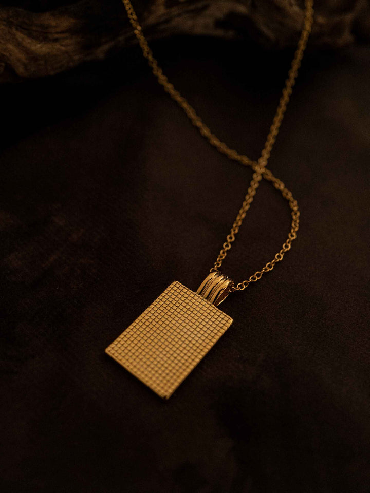 A gold necklace with a rectangular pendant