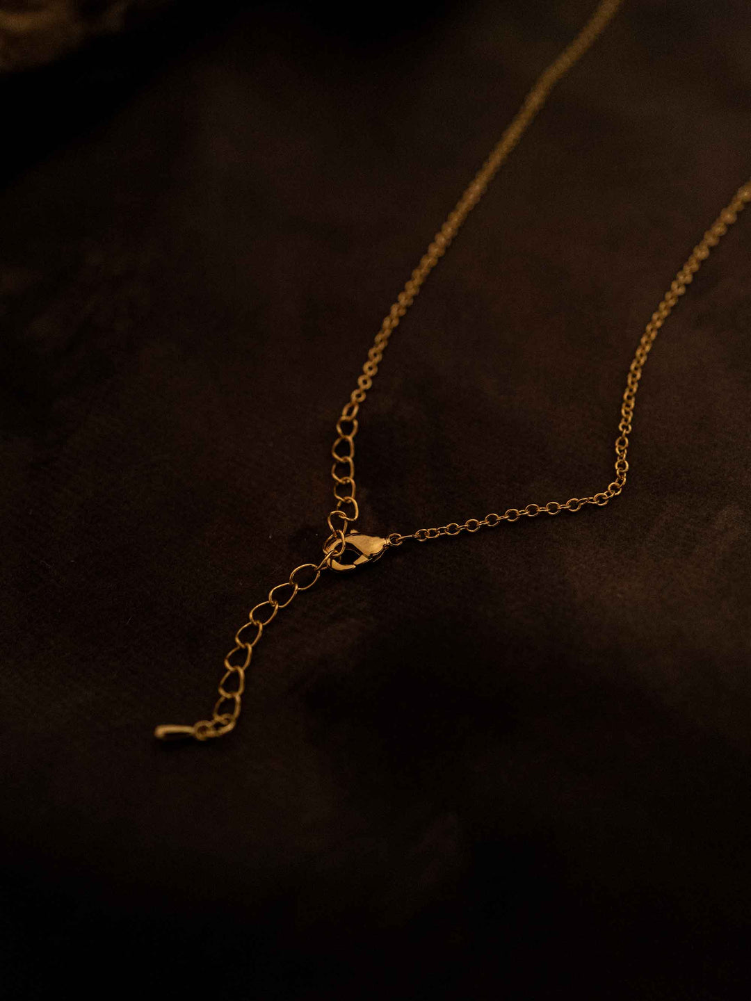 A gold necklace with a rectangular pendant