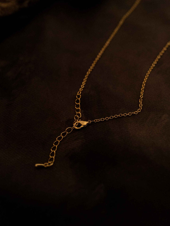 A gold necklace with a rectangular pendant