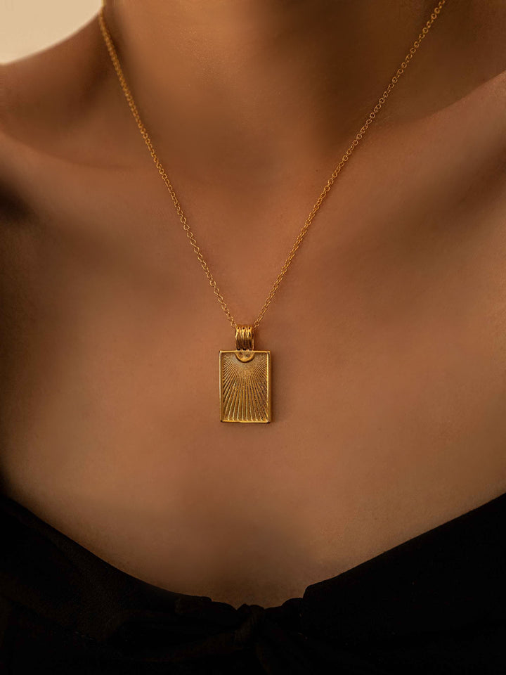 a model wear A gold necklace with a rectangular pendant