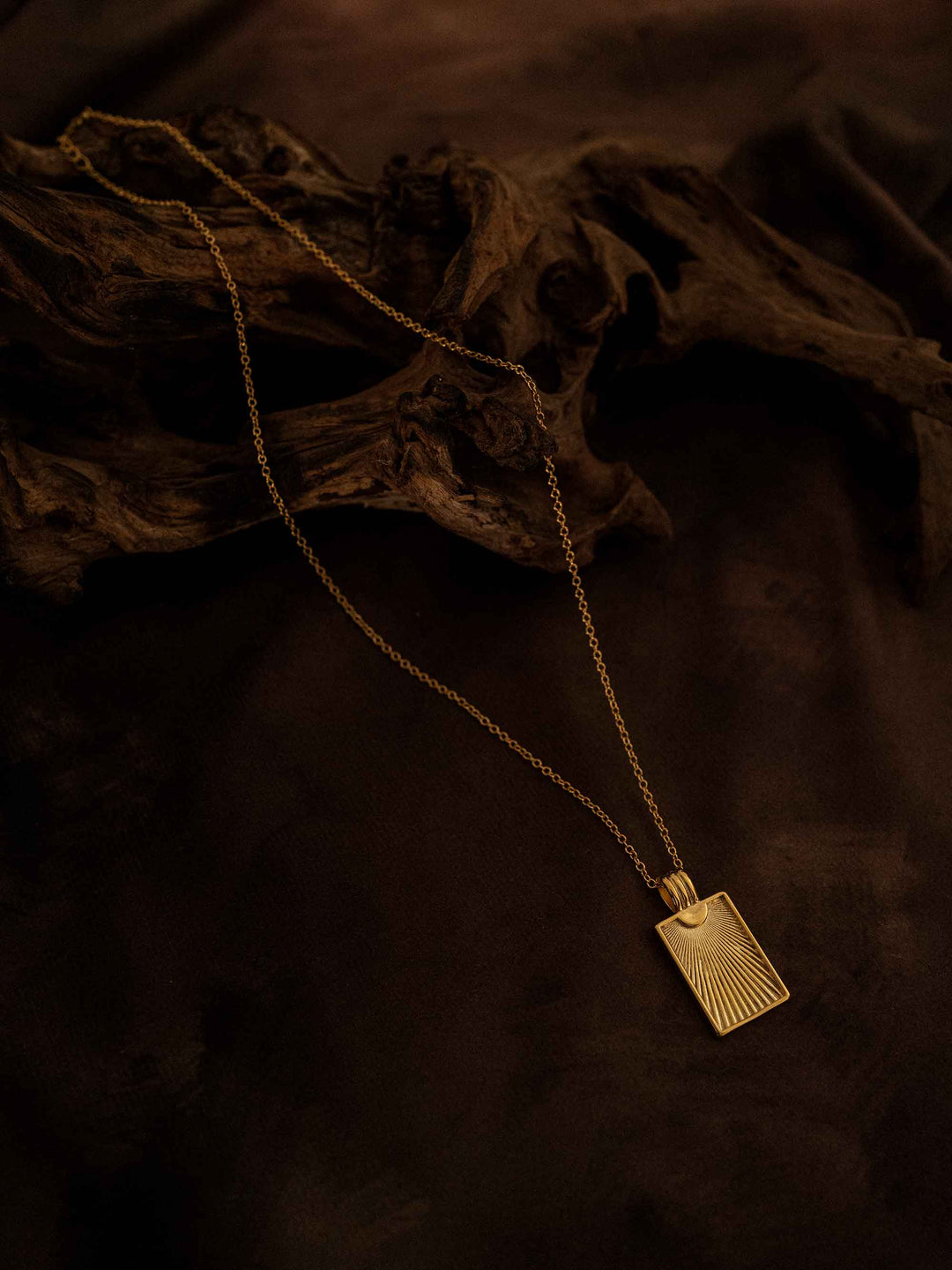 A gold necklace with a rectangular pendant