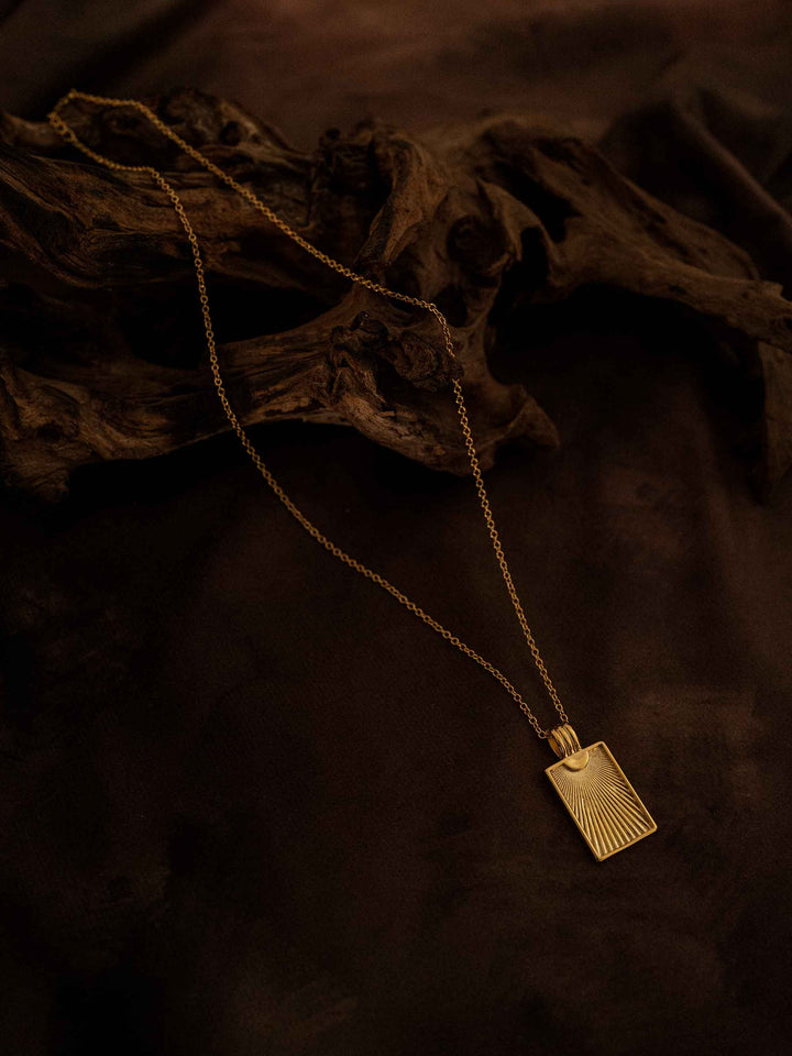 A gold necklace with a rectangular pendant
