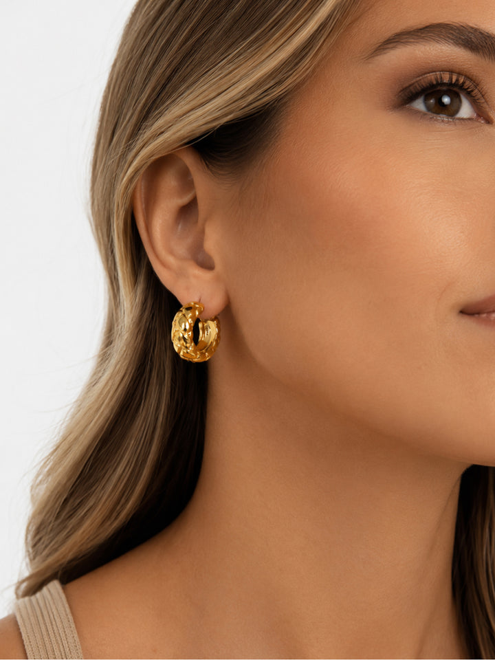 Gold-plated woven hoop earrings worn close to the ear