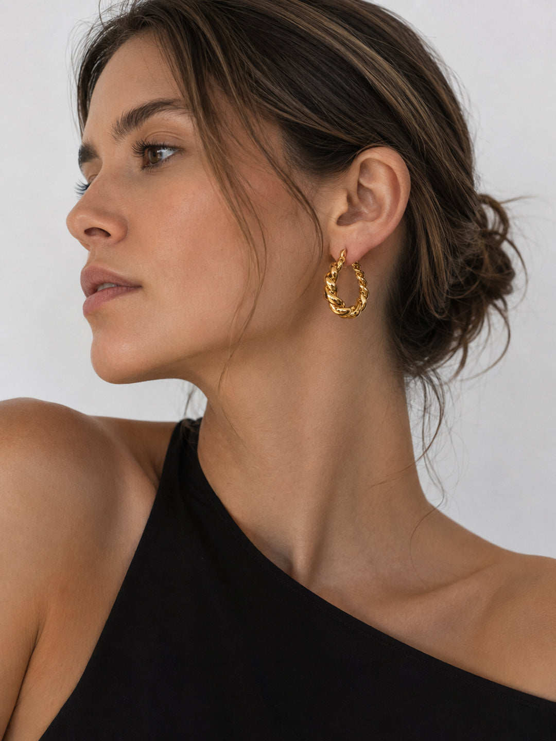 Gold-plated twisted hoop earrings worn close to the ear