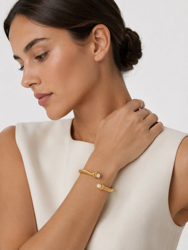 Gold-plated pearl cuff bracelet worn with neutral outfit