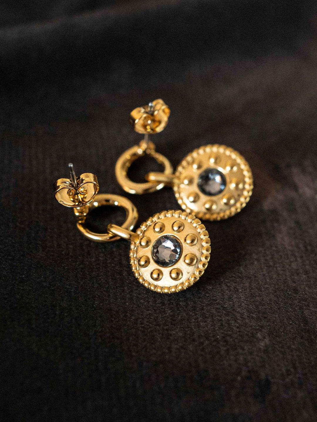 A pair of golden earrings with black crystal onyx