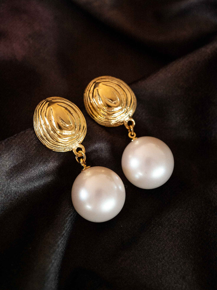A pair of earrings with large golden pearls