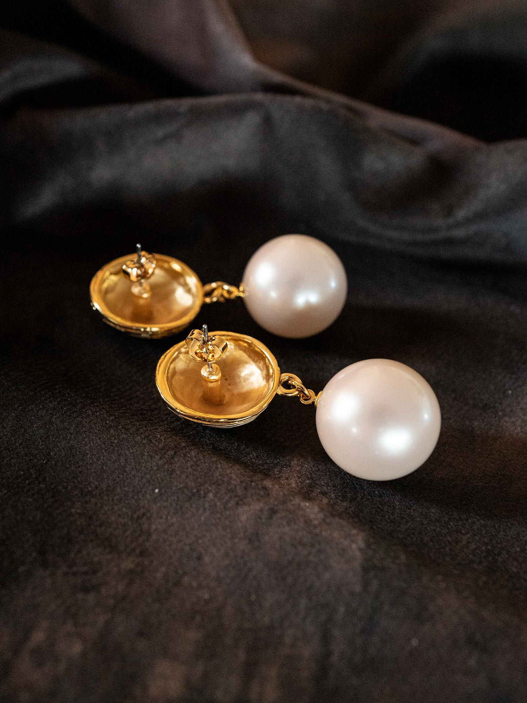 A pair of earrings with large golden pearls