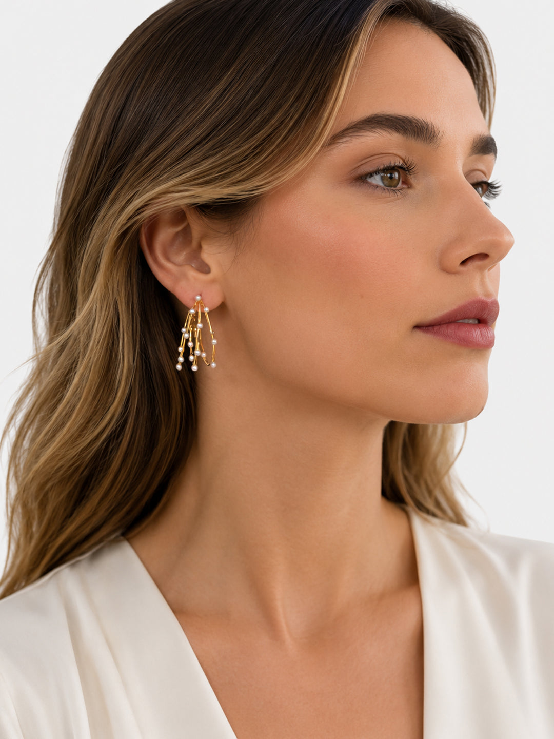Gold-plated pearl hoop earrings worn with white outfit