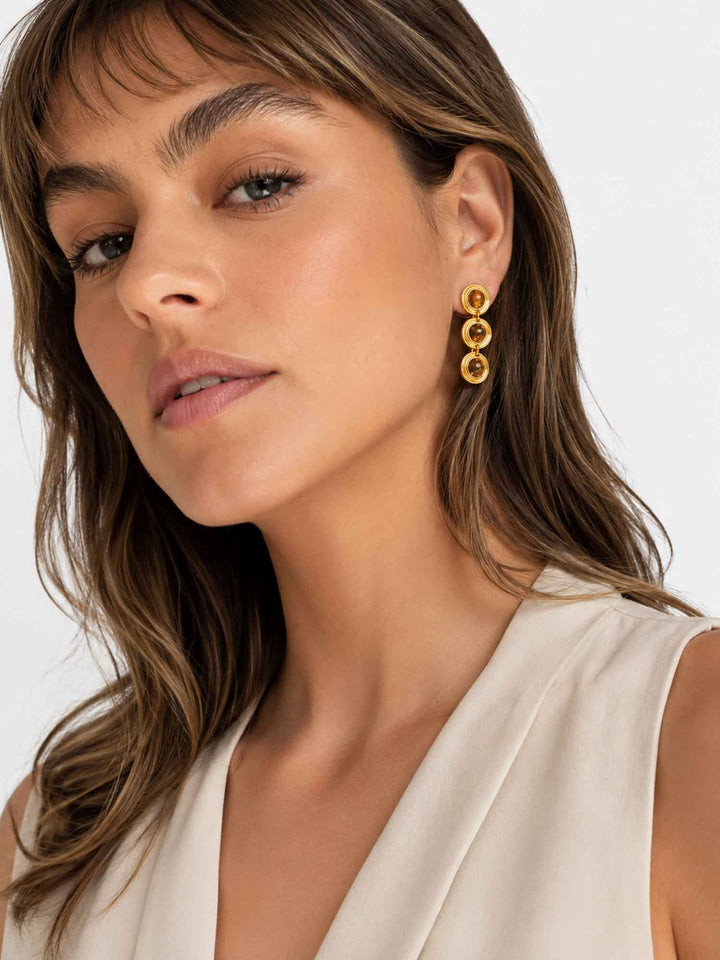 Close-up view of model wearing Alanis tiger eye gold drop earrings