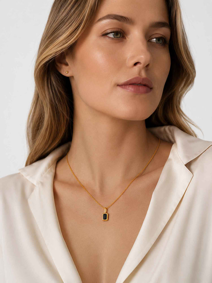 Close-up view of model wearing Clelia black cubic zirconia gold pendant necklace