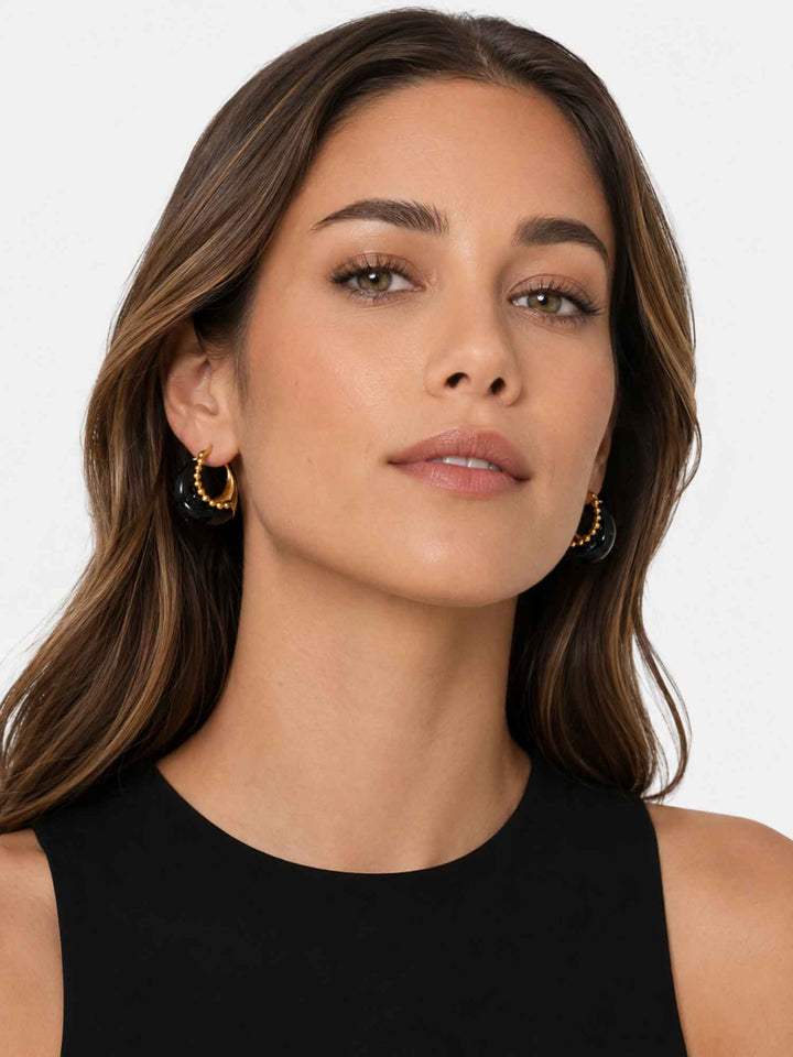 Model wearing Brina black and gold hoop earrings with statement styling