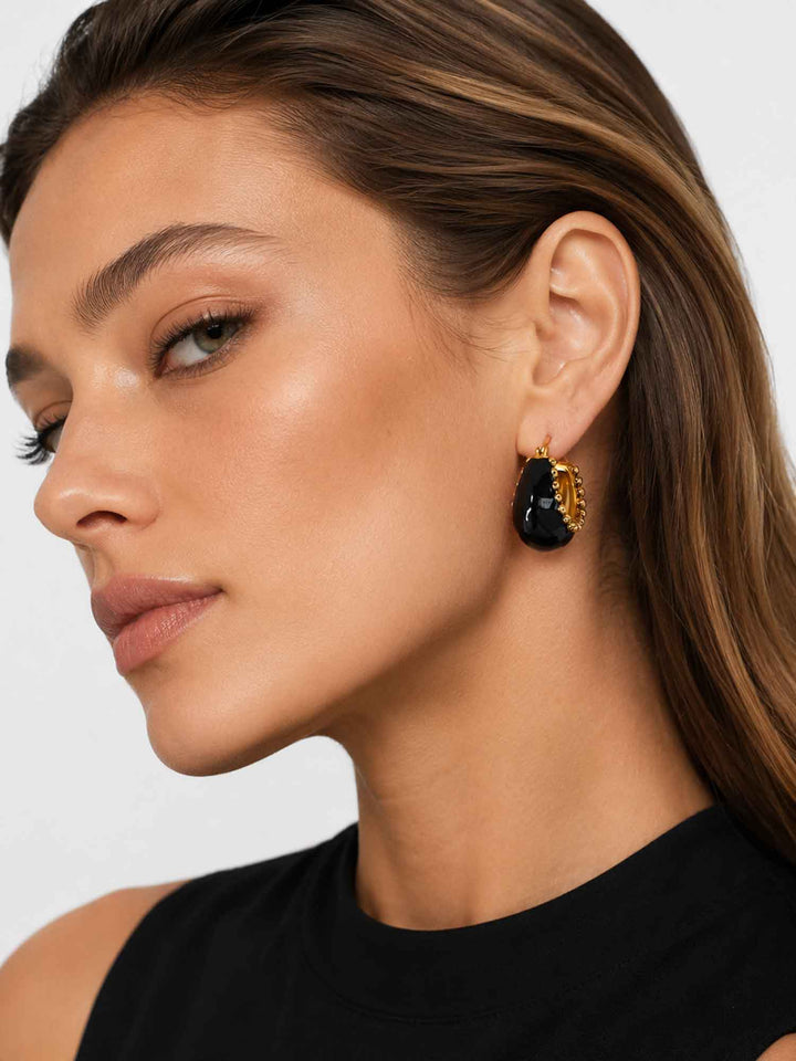 Side view of model wearing Brina black and gold hoop earrings