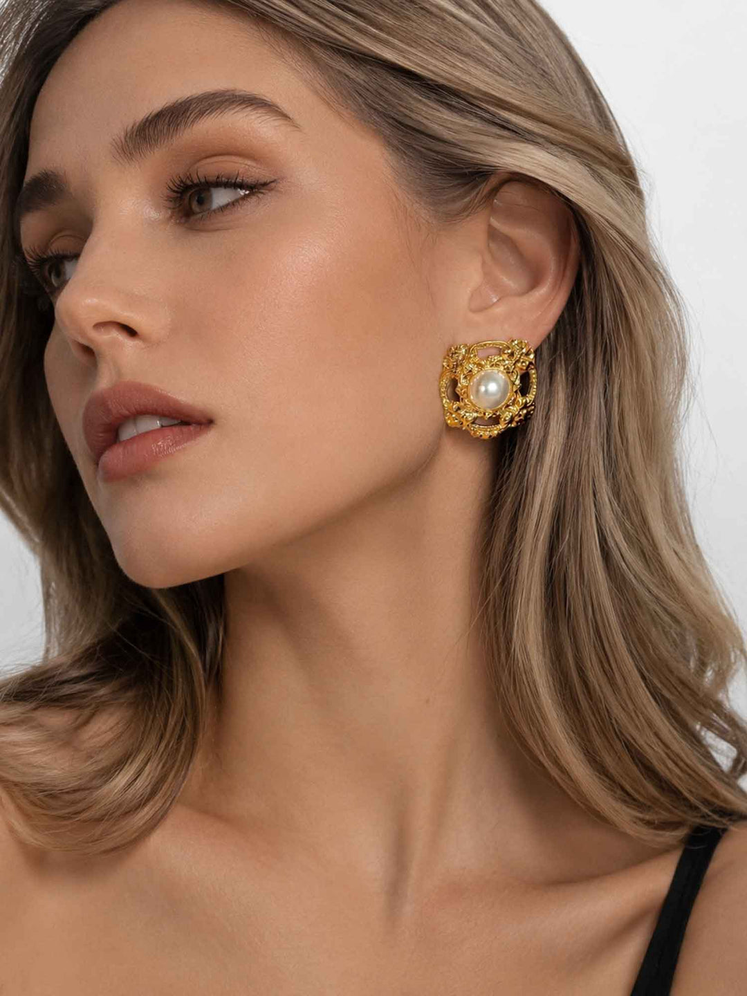 Close-up view of model wearing classic acrylic pearl gold stud earrings