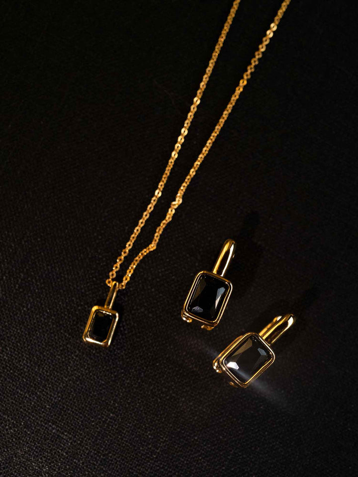 Clelia black cubic zirconia hoop earrings styled with matching necklace on dark background
