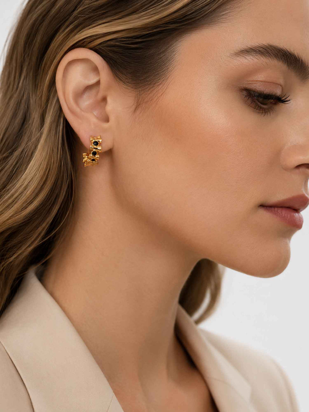 Side view of model wearing Eudora black onyx gold huggie hoop earrings