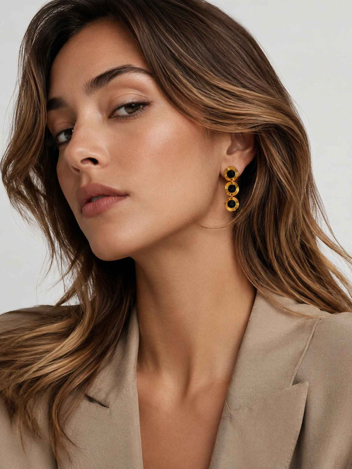 Model wearing Evienne black crystal gold drop earrings with beige blazer styling