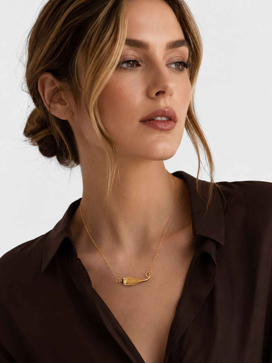Model wearing Fernanda gold shell pendant necklace with elegant dark styling