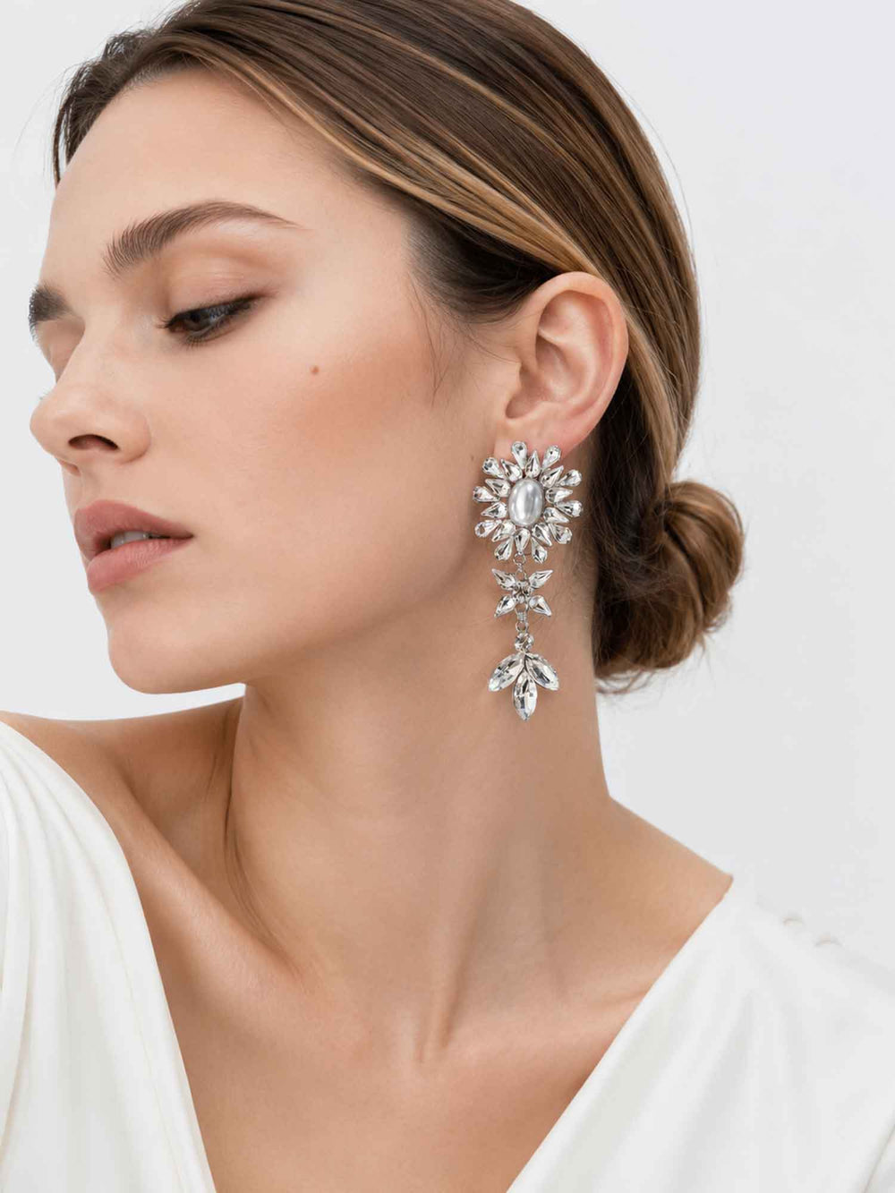 Side view of model wearing Haven silver crystal pearl drop earrings with white outfit
