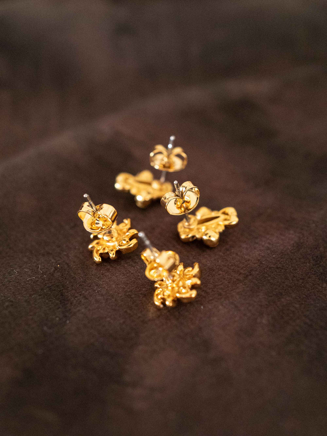 Iris floral gold mini hoop earring set styled on dark fabric