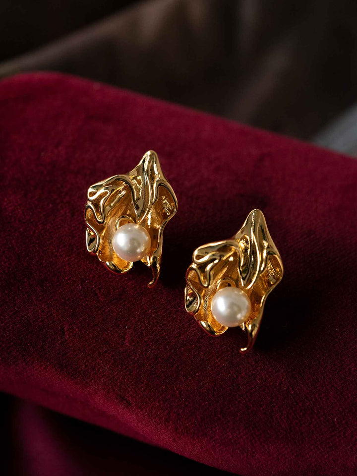 Minette sculptural pearl gold stud earrings styled on red fabric