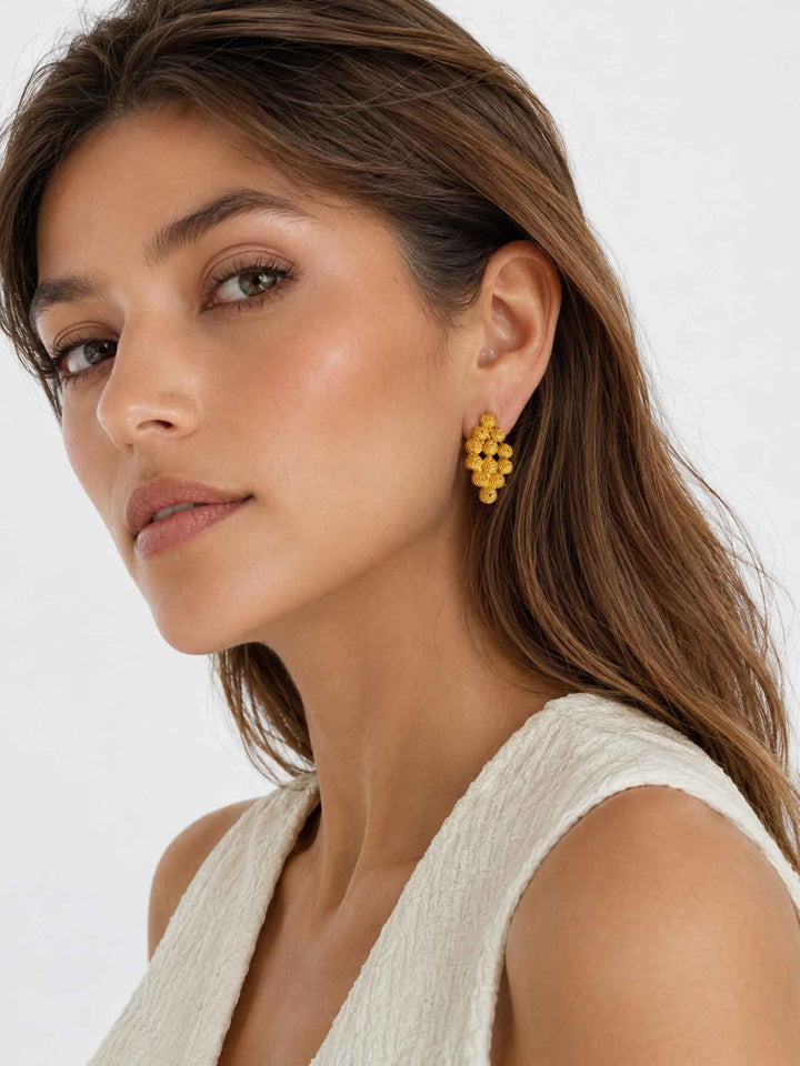 Model wearing Nicola textured gold cluster stud earrings with elegant styling