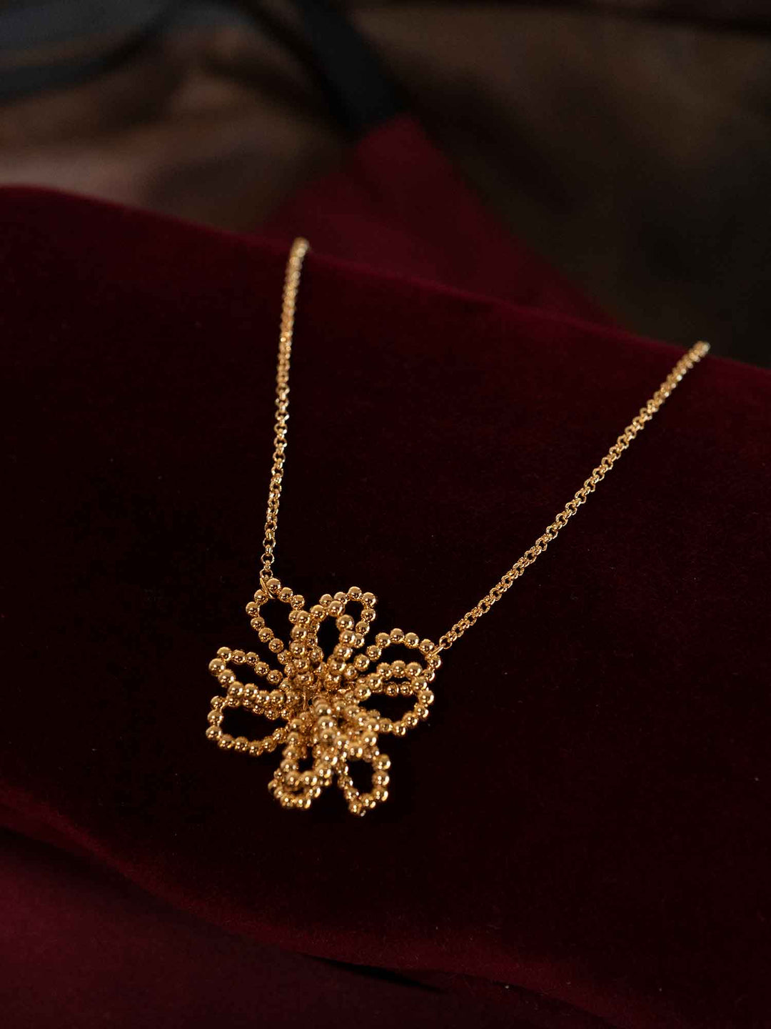 Olyssa beaded flower gold pendant necklace styled on red fabric