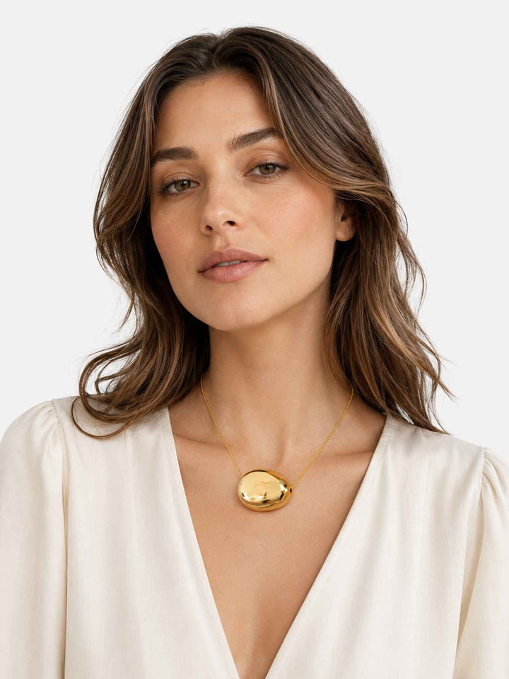 Model wearing Paulina gold dome pendant necklace with white outfit