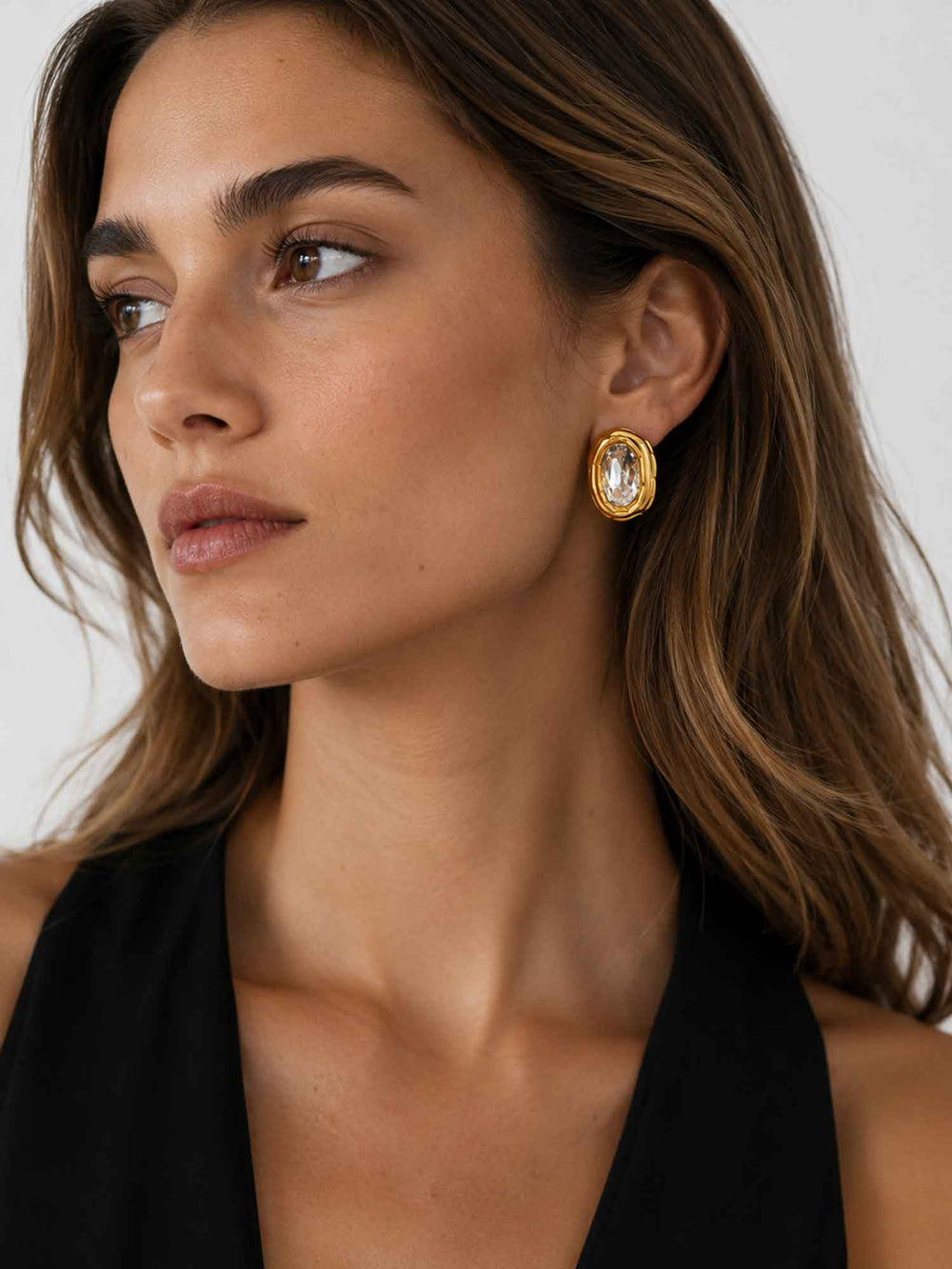 Model wearing Sparkle oval crystal gold stud earrings with black outfit