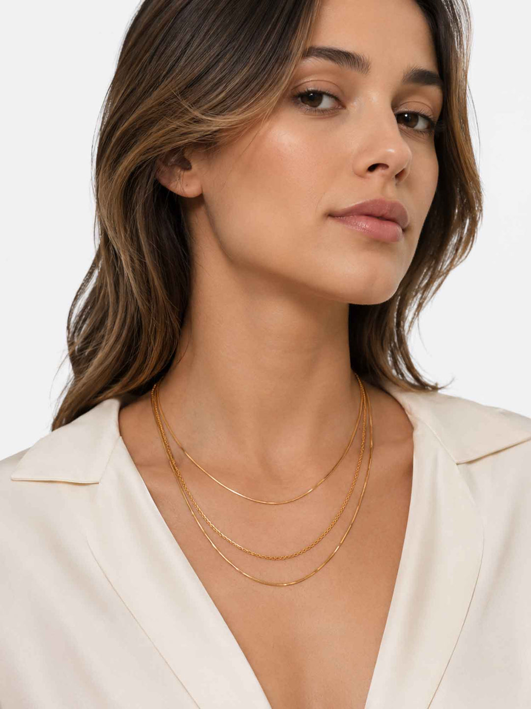 Close-up view of model wearing Thesira layered gold chain necklace