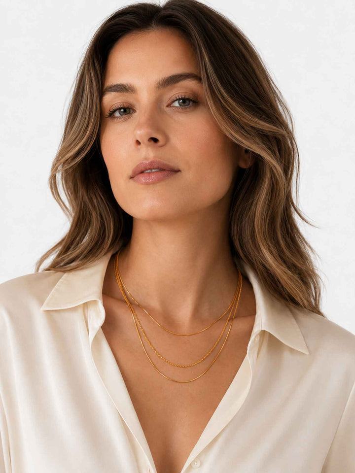Model wearing Thesira layered gold chain necklace with white outfit