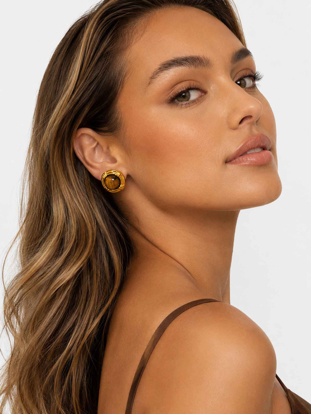 Model wearing tiger eye stone gold stud earrings with elegant styling