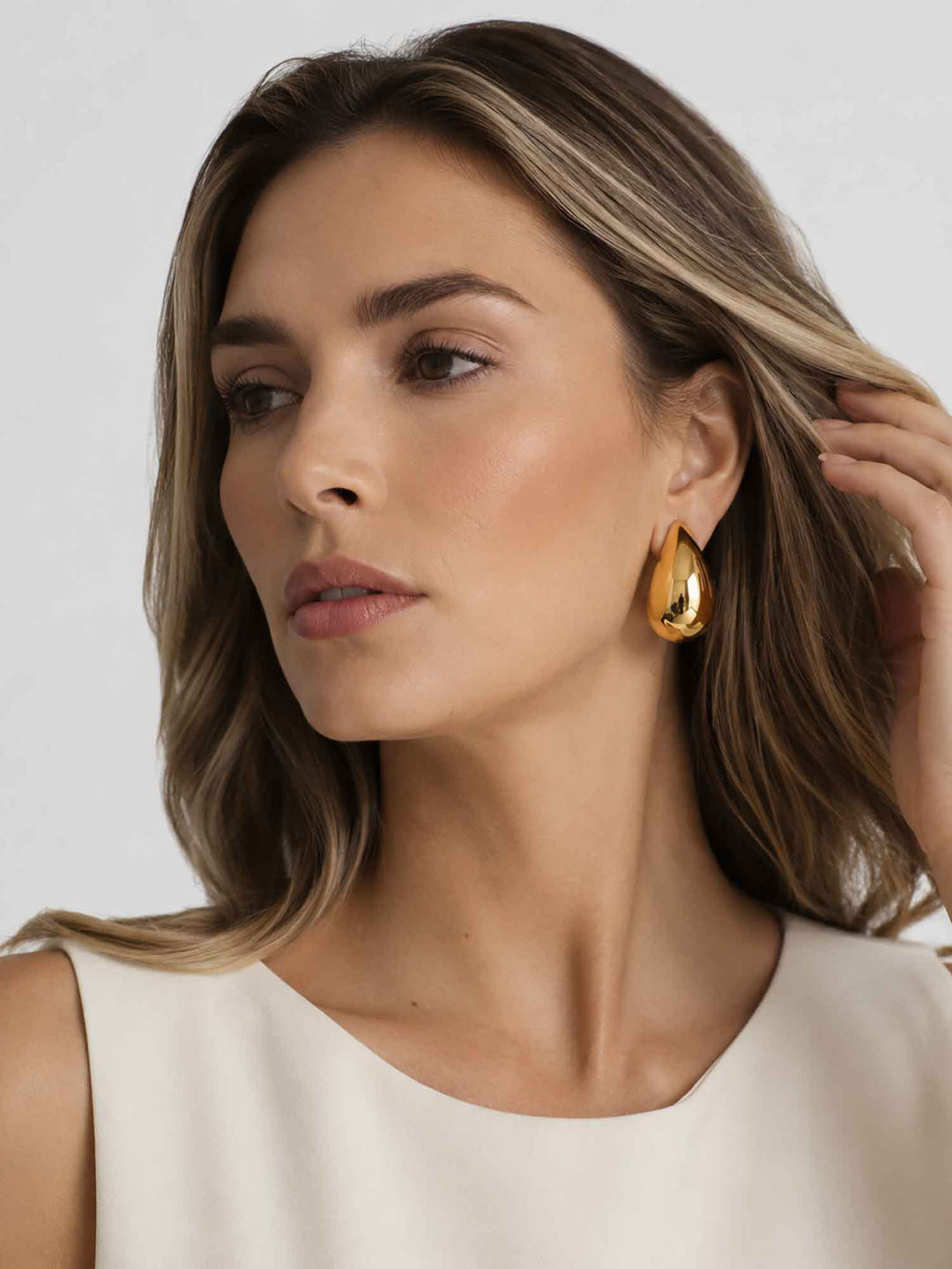Model wearing Titania large gold teardrop earrings with elegant white