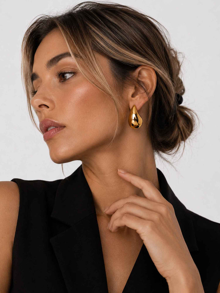 Model wearing Titania medium gold teardrop earrings with a polished statement look