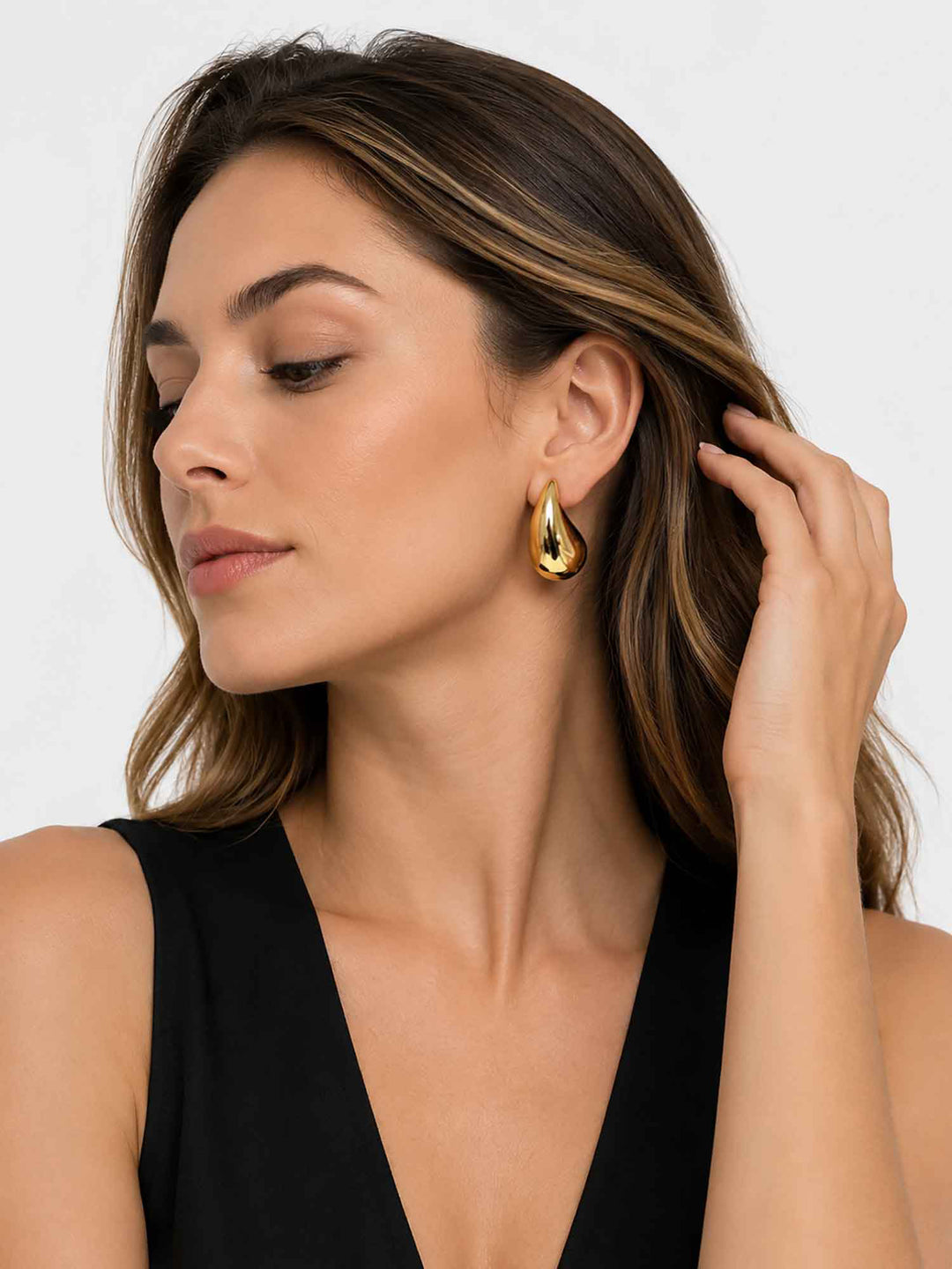 Profile view of model wearing Titania medium gold teardrop earrings