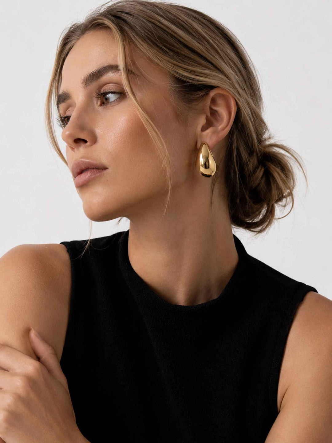 Model wearing Titania medium gold teardrop earrings with elegant styling