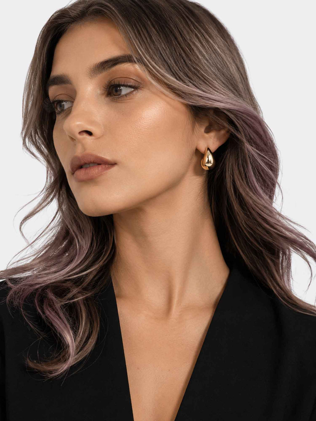 Model wearing Titania small gold teardrop earrings with elegant styling