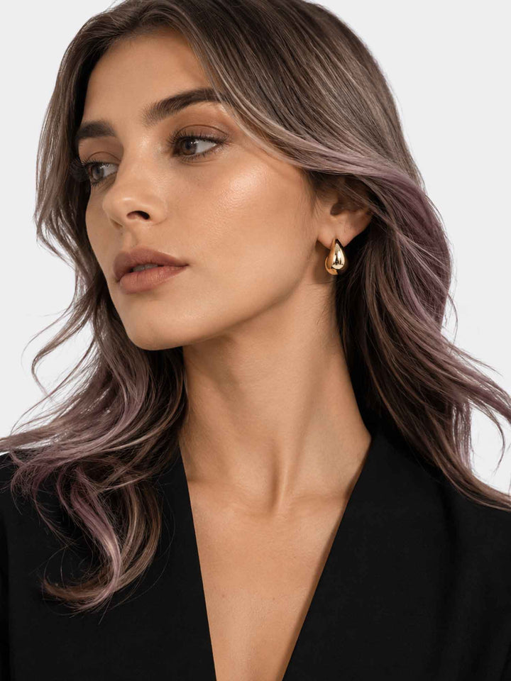 Model wearing Titania small gold teardrop earrings with elegant styling