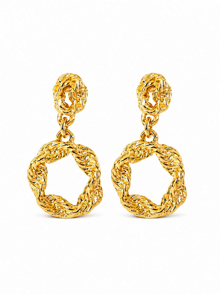 Pair of twisted gold hoop drop earrings on white background