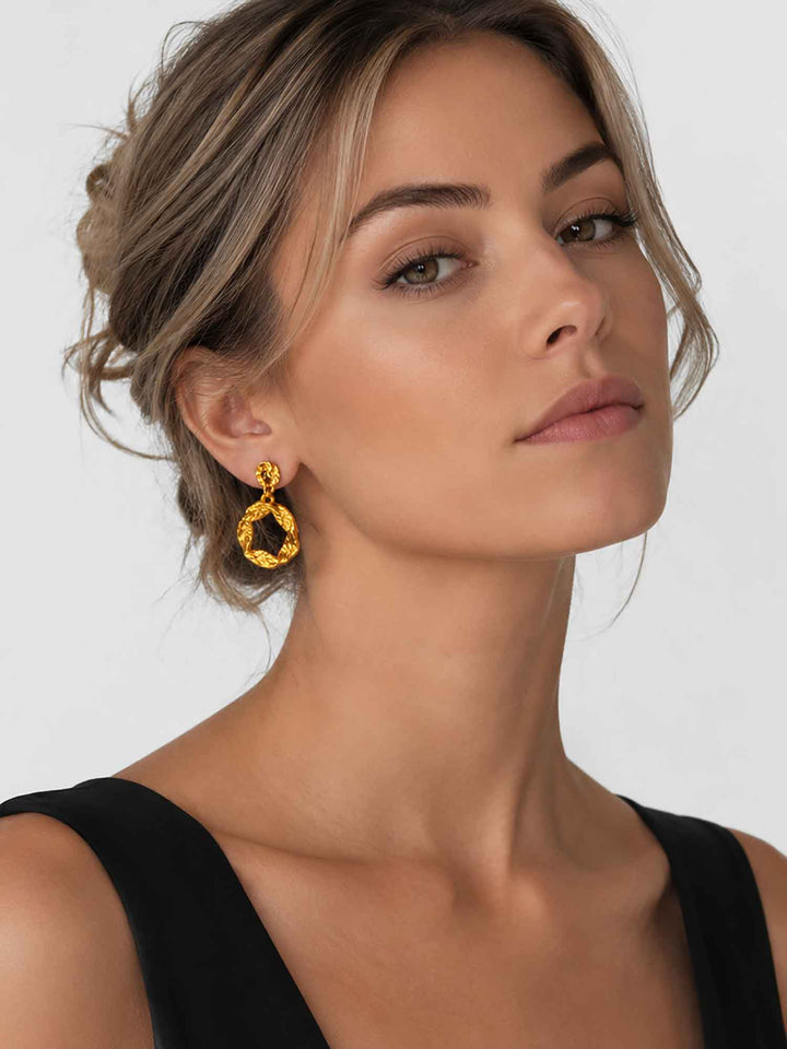 Model wearing twisted gold hoop drop earrings with evening styling