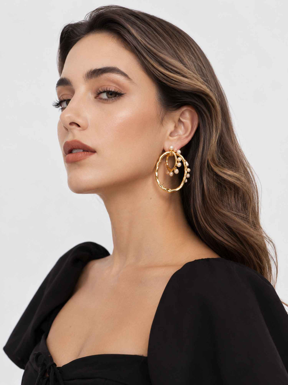 Model wearing two-way detachable cotton pearl gold hoop earrings with black outfit