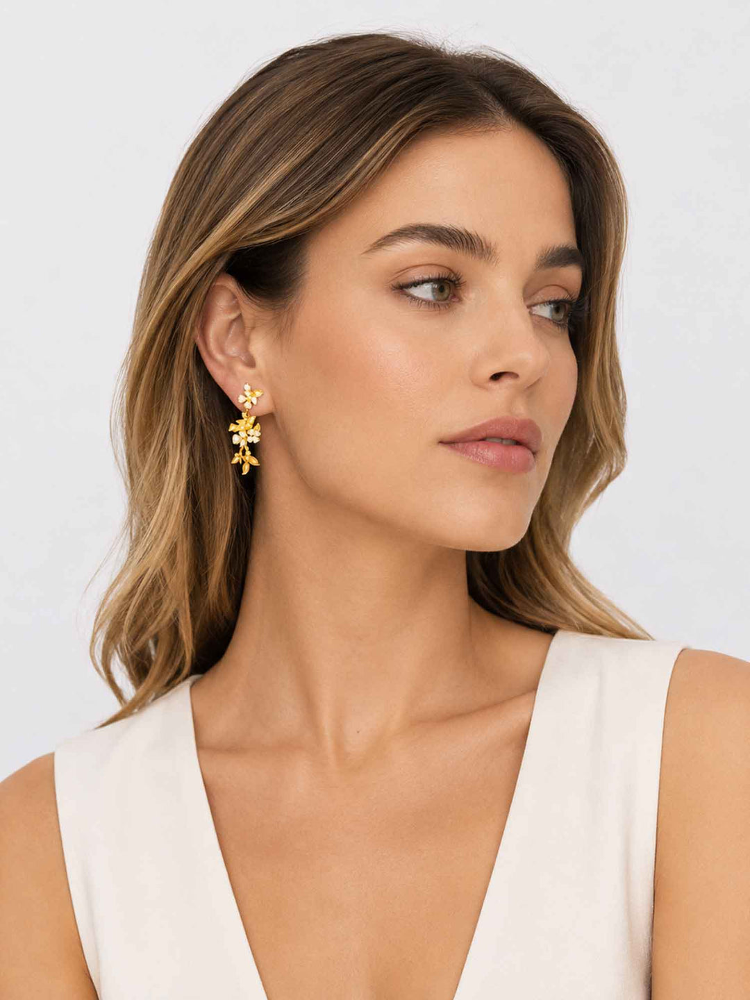 Side view of model wearing white floral bird gold drop earrings