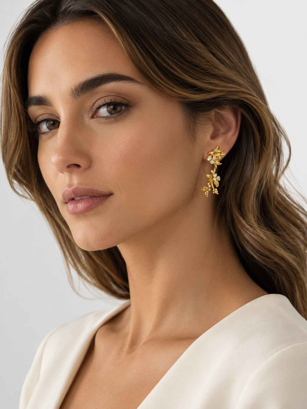 Model wearing white floral bird gold drop earrings with white outfit