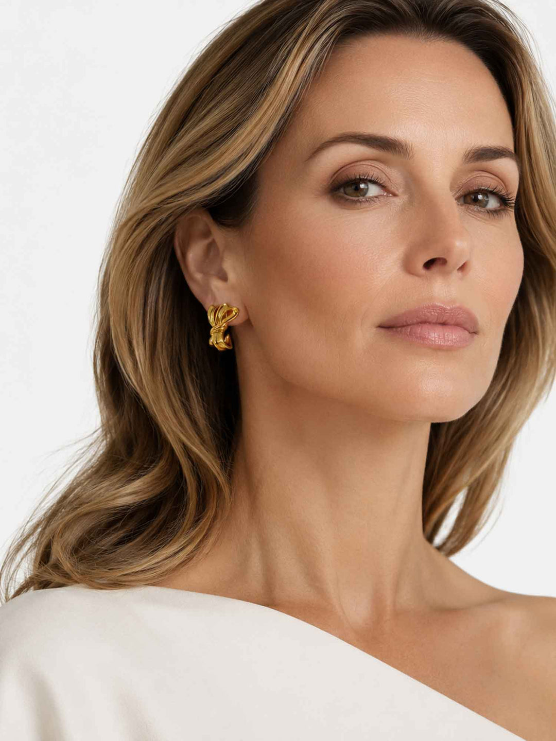 Model wearing Zaya sculptural gold ribbon stud earrings with elegant styling