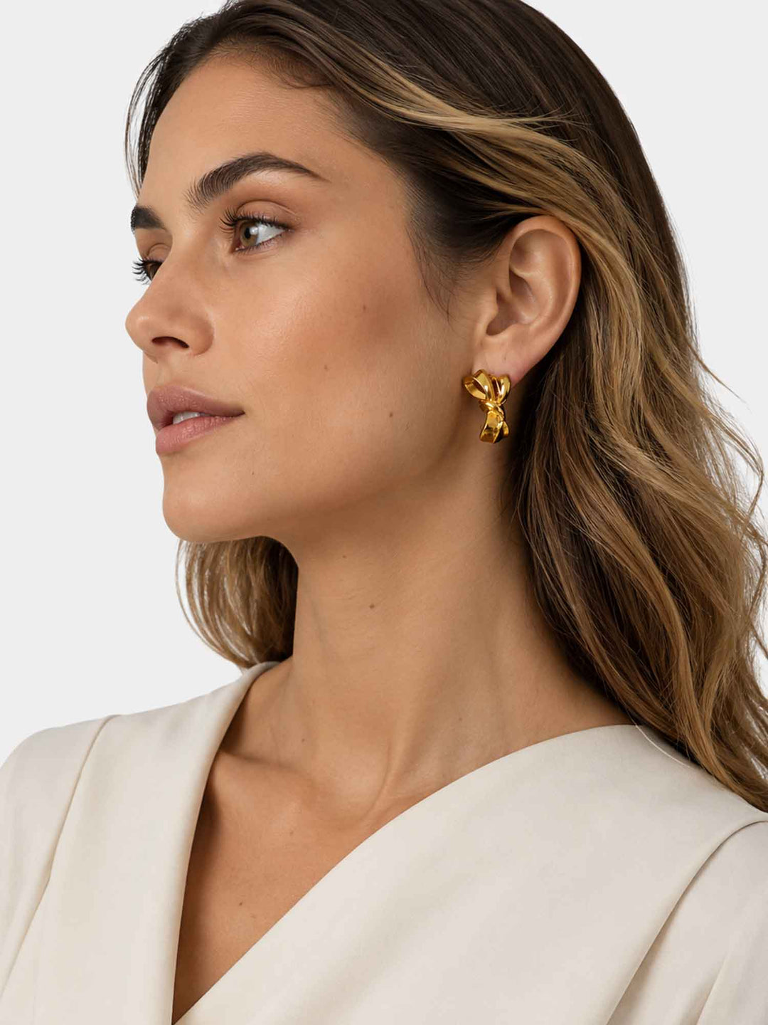 Side view of model wearing Zaya sculptural gold ribbon stud earrings