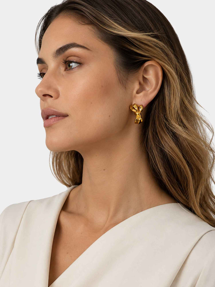 Side view of model wearing Zaya sculptural gold ribbon stud earrings